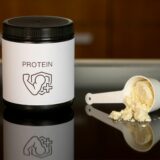 プロテインのボトルとスプーンからこぼれ落ちるパウダー